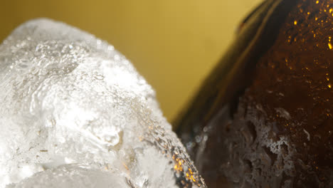 Nahaufnahme-Von-Kondensationstropfen,-Die-An-Glasflaschen-Mit-Kaltem-Bier-Oder-Erfrischungsgetränk-Herunterlaufen-Und-In-Einem-Mit-Eis-Gefüllten-Eimer-Vor-Gelbem-Hintergrund-Abkühlen-3